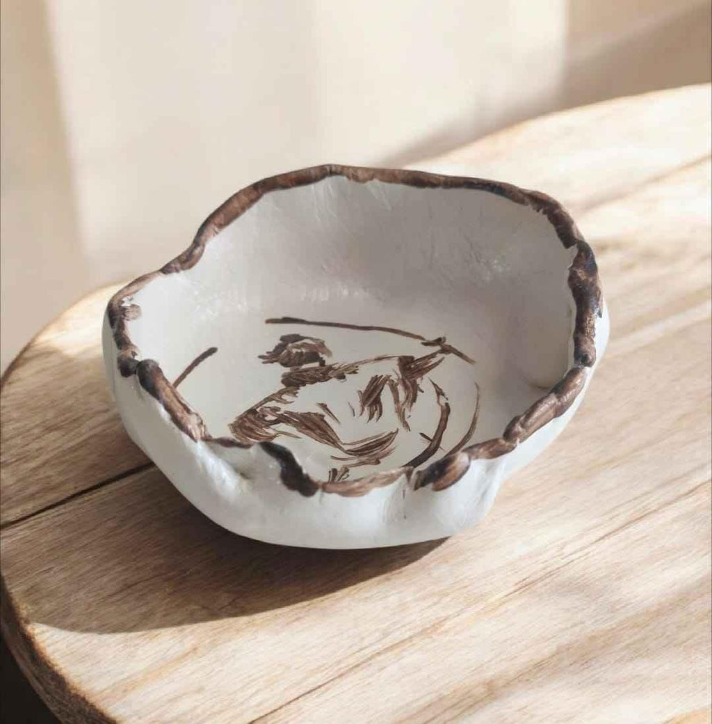 Handgemachte Keramikschale mit brauner Acrylmalerei, unregelmäßiger Rand, auf Holztisch